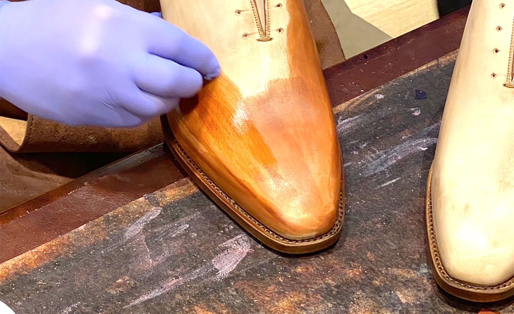 Ambachtsman brengt met de hand kleur aan op een leren schoen